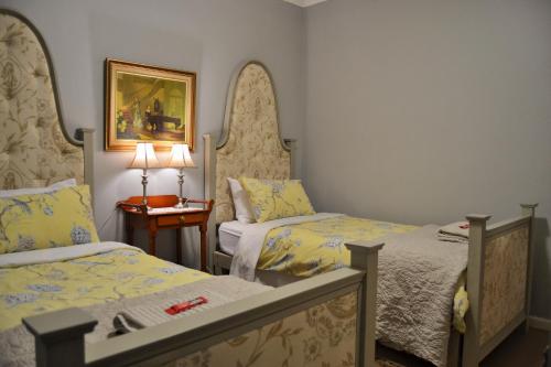 a bedroom with two beds and a table with a lamp at Versailles Self-Catering in Wellington