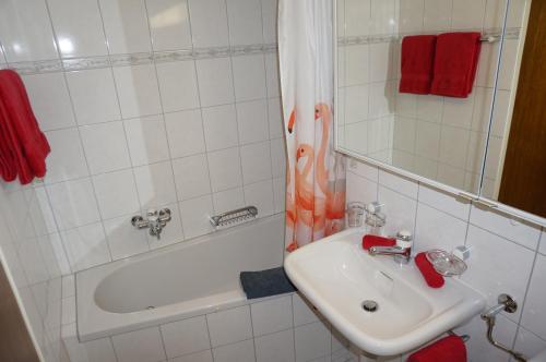 a white bathroom with a sink and a bath tub at Studio Willimann Haus Dala im 4 Stock in Leukerbad