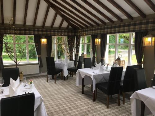 a dining room with white tables and chairs and windows at Greshornish House Hotel in Edinbane