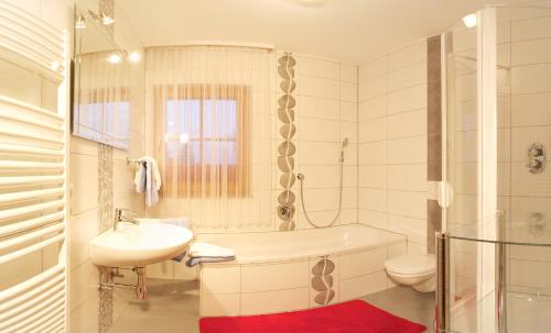 a bathroom with a tub and a sink and a toilet at Almhaus Karantanien in Hochrindl