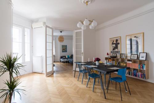una sala da pranzo e un soggiorno con tavolo e sedie. di Klauzal apartment w/3 bedrooms, french balcony a Budapest