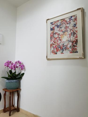 a painting on a wall next to a table with flowers at For You Hostel in Yeosu