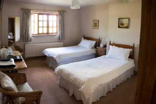a bedroom with two beds and a table and a desk at Larkrise Cottage Bed And Breakfast in Stratford-upon-Avon
