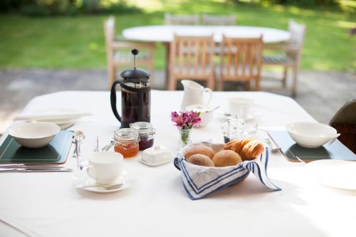 een witte tafel met croissants en kopjes en een waterkoker bij Larkrise Cottage Bed And Breakfast in Stratford-upon-Avon