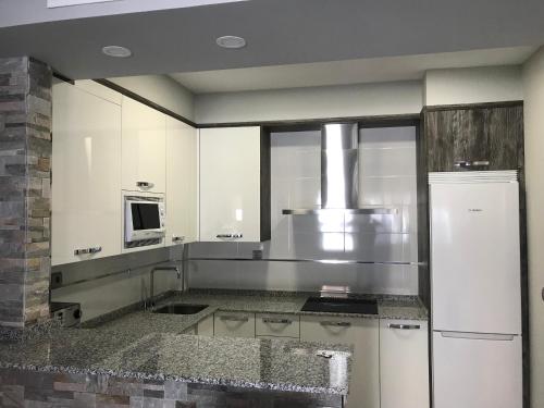 a kitchen with white cabinets and a refrigerator at Nicoletta in Madrid
