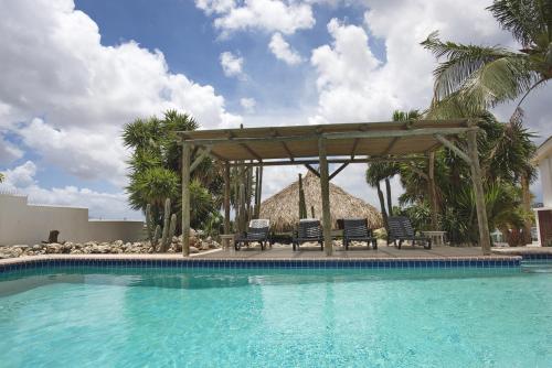 a pool with chairs and a gazebo next to a resort at Bantopa Apartments in Willemstad