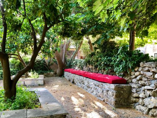 a stone wall with a red bench in a garden at Masseria Li Reni in Manduria