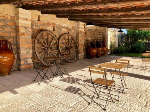 a group of tables and chairs next to a wall at Masseria Li Reni in Manduria