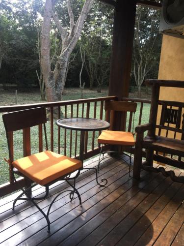 a porch with two chairs and a table on a deck at Calcada Sao Jose in Tiradentes