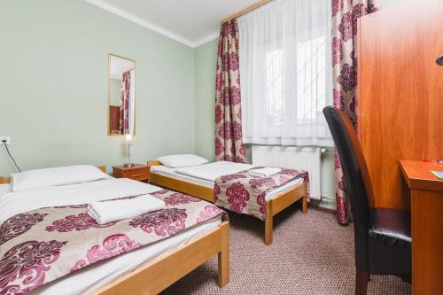 een kamer met 2 bedden, een bureau en een raam bij Hostel Biały Dom in Krakau