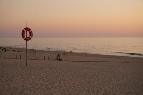 a beach at sunset with a red life preserver at Holiday House Tocha in Palheiros da Tocha