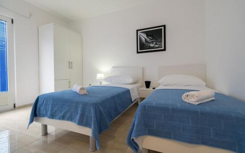 two beds in a white room with blue sheets at Villa Doris in Neum