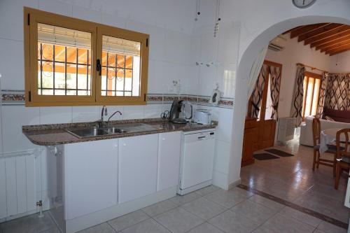 Una cocina con gabinetes blancos y un fregadero. en Muriel House, en Monte Pego