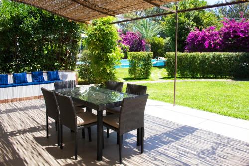 a table and chairs on a patio with a garden at The Green Seaside in Fondachello
