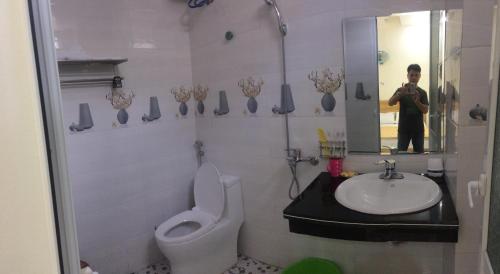 a man taking a picture of a bathroom with a toilet and sink at Homestay Thanh Long in Cat Ba