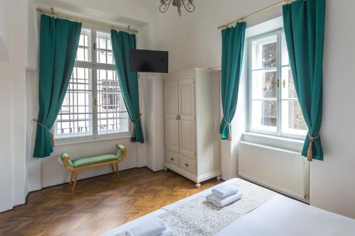 a bedroom with green curtains and a bed and a chair at Barbo Palace Apartments and Rooms in Ljubljana