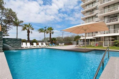 a swimming pool with an umbrella next to a building at Boulevard Towers on Broadbeach in Gold Coast
