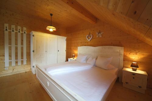 a bedroom with a large white bed in a attic at Almhaus Pleschinhof in Hochrindl