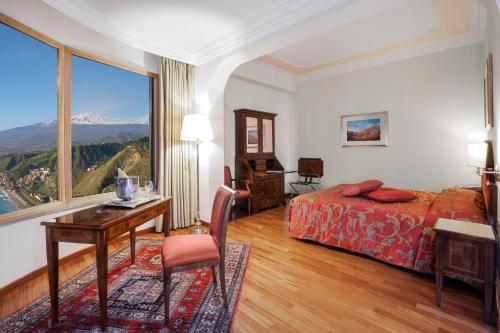 a hotel room with a bed and a desk and a window at Hotel Villa Diodoro in Taormina