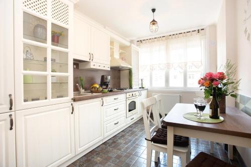 a kitchen with white cabinets and a table with flowers on it at Rox Central Apartments 3 in Timişoara