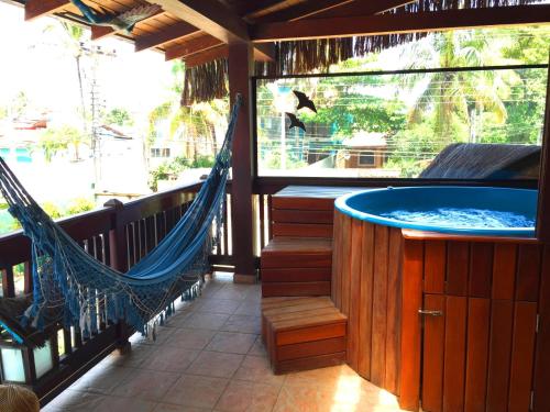 a porch with a hammock and a hot tub at Pousada Pura Vida Maresias in Maresias