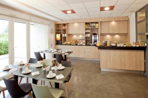 um restaurante com mesas e cadeiras e uma cozinha em Séjours & Affaires Grenoble Marie Curie em Grenoble