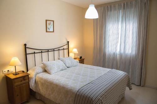a bedroom with a bed and two lamps and a window at Apartamento Torcal Écija in Écija