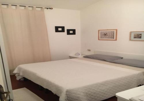 a white bedroom with two beds and a curtain at Casa Asparagi in San Teodoro