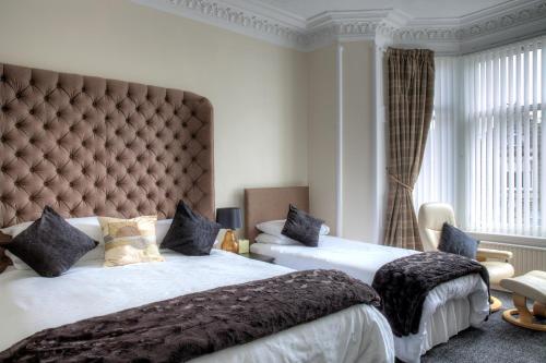a bedroom with two beds and a large headboard at Kildonan Guest House in Aberdeen