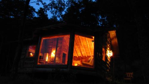 a log cabin at night with lights in the window at Mallin Colorado Ecolodge in Aldana