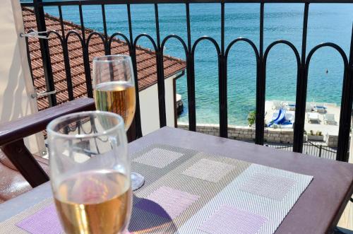 a table with two glasses of wine on a balcony at Apartment The Sea Coast in Kotor