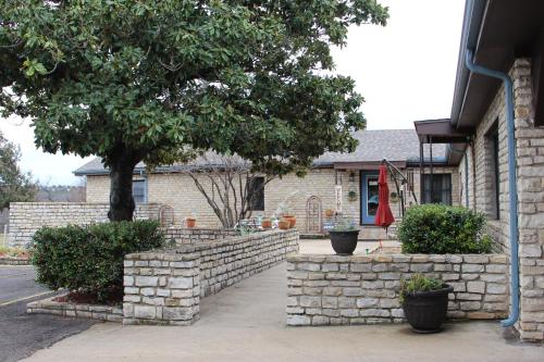 a house with a brick retaining wall and a tree at Live Oak B&B in Glen Rose