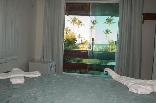 1 dormitorio con 1 cama y una ventana con palmeras en João Praia Hotel, en Maraú