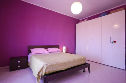 a bedroom with purple walls and a bed with pink pillows at Appartamento con Vista a Venturina in Venturina Terme