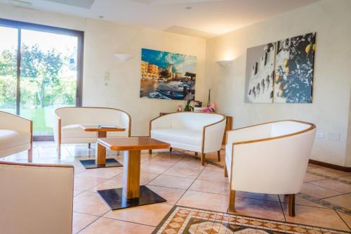 a waiting room with white chairs and tables at Hotel Porto Azzurro in Sirmione