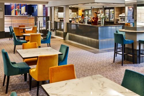 a restaurant with tables and chairs and a bar at Mercure Bolton Georgian House Hotel in Bolton