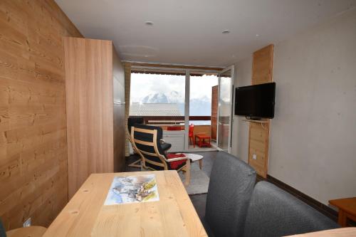 a room with a table and chairs and a television at Le Lauranoure - 205 in L'Alpe-d'Huez