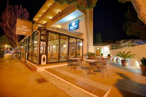 a restaurant with tables and chairs outside at night at Bell Port Hotel in Cala Ratjada