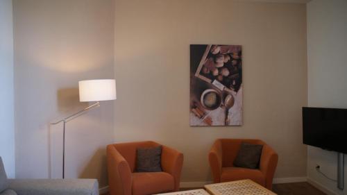 a living room with two chairs and a painting on the wall at In den Roden Leeuw van Limburg in Wittem