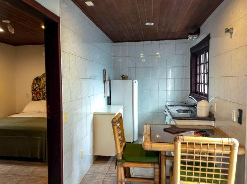 a small kitchen with a table and a refrigerator at Pousada Pura Vida Maresias in Maresias