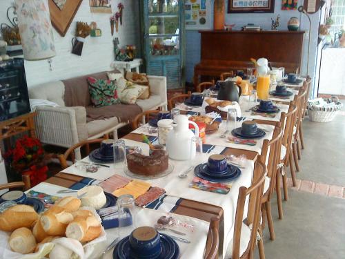 een lange tafel gevuld met brood en borden voedsel bij Pousada Recanto das Girafas in Cunha