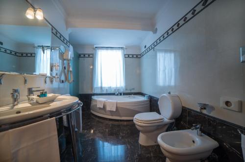 a bathroom with a toilet, sink, and bathtub at Hotel Nettuno in Catania