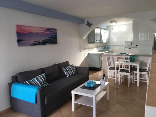ein Wohnzimmer mit einem Sofa und einem Tisch sowie eine Küche in der Unterkunft apartamento pueblo rocio 80 in Nerja