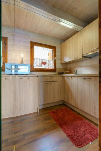 a kitchen with wooden cabinets and a red rug at Agriturismo Giacomino in Gera Lario