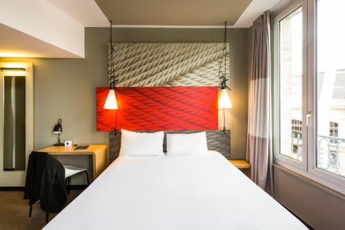 a hotel room with a bed and a desk and a window at ibis Bordeaux Centre Gare Saint Jean Euratlantique in Bordeaux
