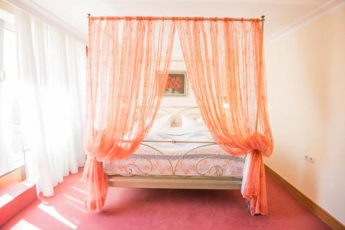 a bedroom with a bed with an orange curtain at Ringhotel Alpenhof - Patchworkhotel in Augsburg