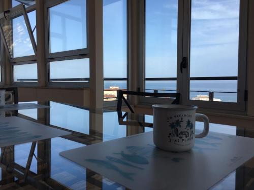 a coffee cup sitting on a table in a room with windows at Blue Sky Apartments in Capo dʼOrlando