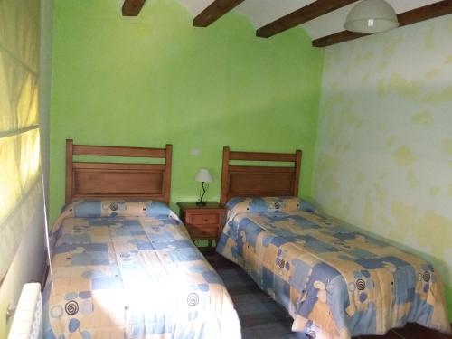 2 camas en una habitación con paredes verdes en Apartamentos las Fuentes del Alto Tajo, en Peralejos de las Truchas