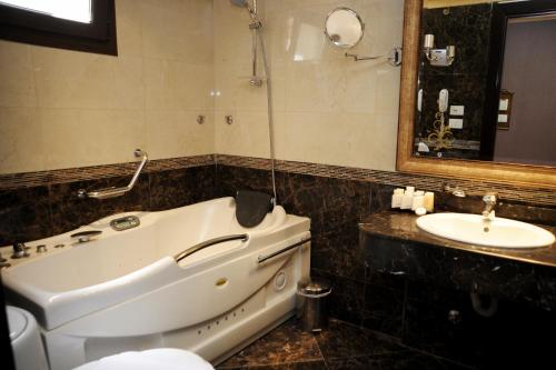 a bathroom with a bath tub and a sink at Q Hotel in Beirut