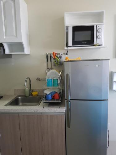 a kitchen with a refrigerator and a sink and a microwave at KC Studio 1 at Horizons 101 Cebu in Cebu City